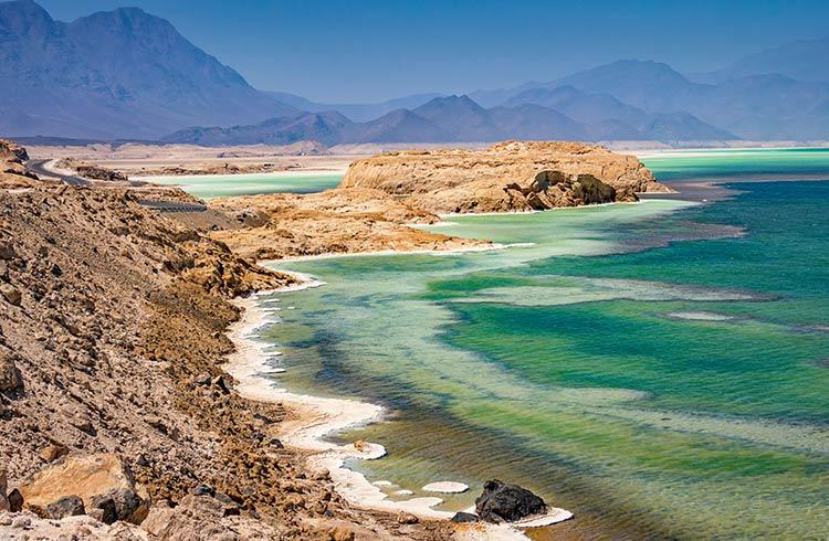 Lake Assal Djibouti Day Trip and Tour Experience Travelers admiring Lake Assal during 4-day Djibouti tour Tourists walking on salt flats during 2-day Djibouti trip to Lac Assal Volcanic landscape between Djibouti City and Lac Assal Local tour guide explaining Lac Assal history to visitors Comfortable 4x4 vehicle for 2-day Djibouti trip from the city